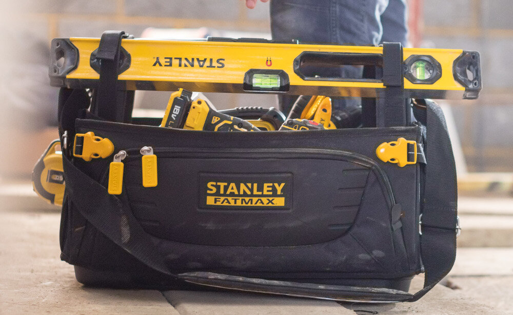 Torba narzędziowa STANLEY Fatmax Quick Access FMST1-80146 pomieszczenie betonowa podłoga torba wypełniona narzędziami w tle stoi osoba organizacja pracy porządek wśród narzędzi