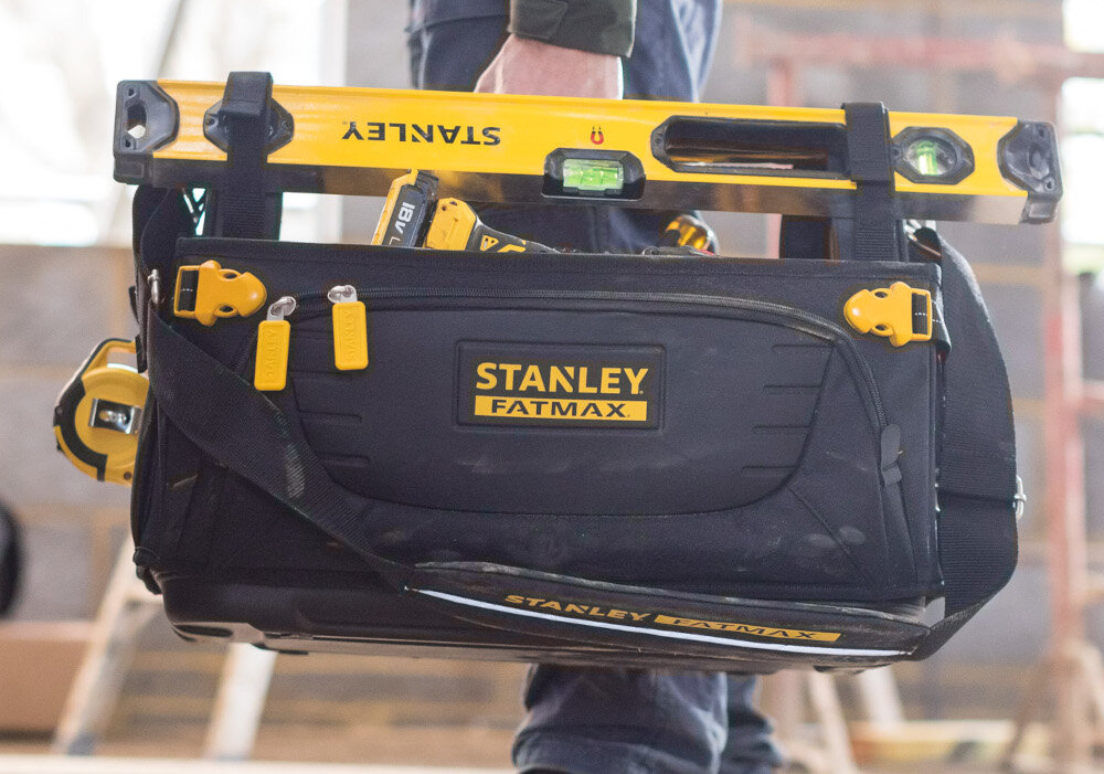 Torba narzędziowa STANLEY Fatmax Quick Access FMST1-80146 pomieszczenie osoba trzyma torbę w dłoni torba wypełniona narzędziami solidna gumowana rączka regulowany pasek na ramię waga około 3,3 kg ergonomiczna konstrukcja