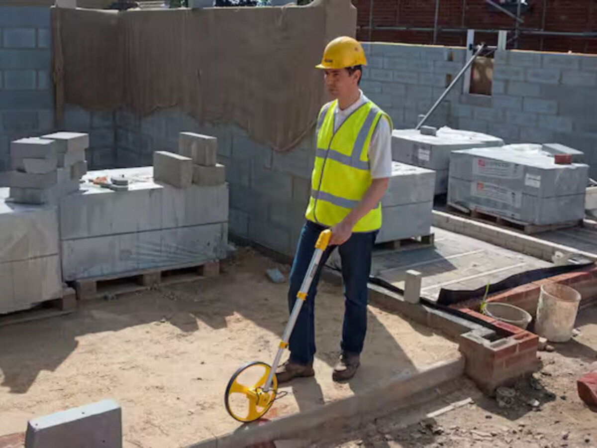 Drogomierz STANLEY MW40M 1-77-174, miara, trasy, precyzja, odmierzenie, mężczyzna odmierza drogomierzem dystans na budowie