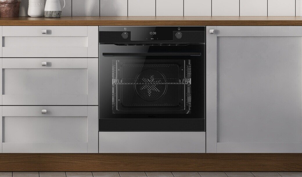 Czarny piekarnik elektryczny wbudowany w białą kuchenną zabudowę z drewnianym blatem. Na panelu sterowania widoczne są dwa pokrętła i wyświetlacz cyfrowy.