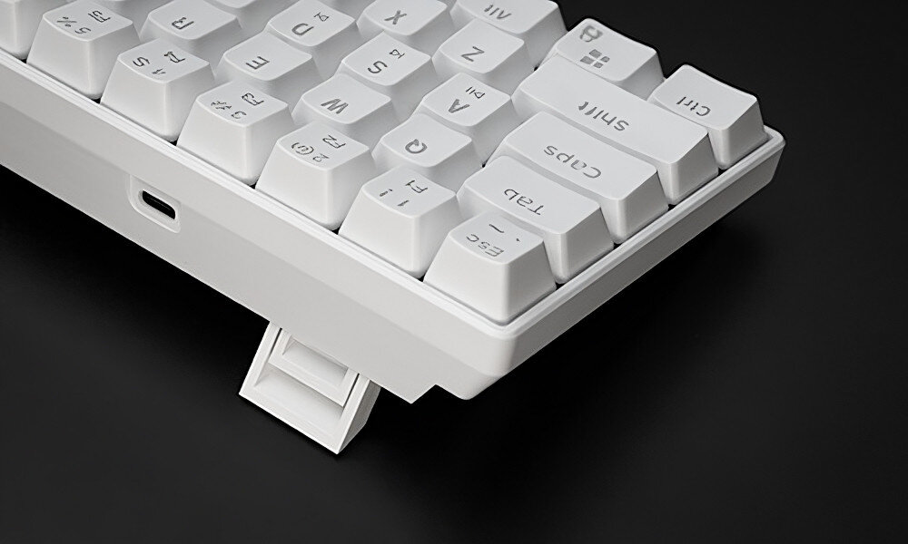 Biała klawiatura z widocznymi klawiszami, takimi jak \'Shift\', \'Caps\', \'Tab\', oraz portem USB. Klawiatura posiada regulowaną podpórkę.