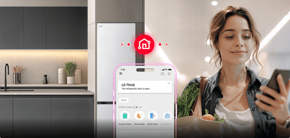 Na obrazie widać nowoczesną kuchnię z białą lodówką LG oraz kobietę trzymającą telefon z aplikacją LG ThinQ, która informuje: \'The refrigerator door is open.\'.