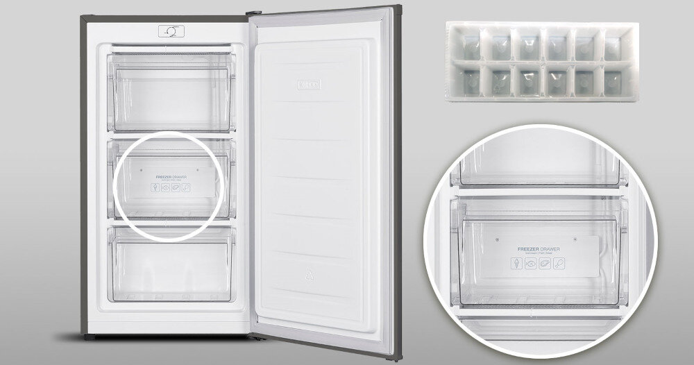 Otwarta zamrażarka z trzema przezroczystymi szufladami, na jednej z nich widoczny napis \'FREEZER DRAWER\'. Obok zamrażarki znajduje się tacka na kostki lodu.