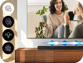 Na drewnianej szafce stoi soundbar z kolorowymi falami świetlnymi. Obok telewizora siedzą dwie osoby pijące napoje, a po lewej stronie widoczne są ikony przedstawiające różne funkcje.