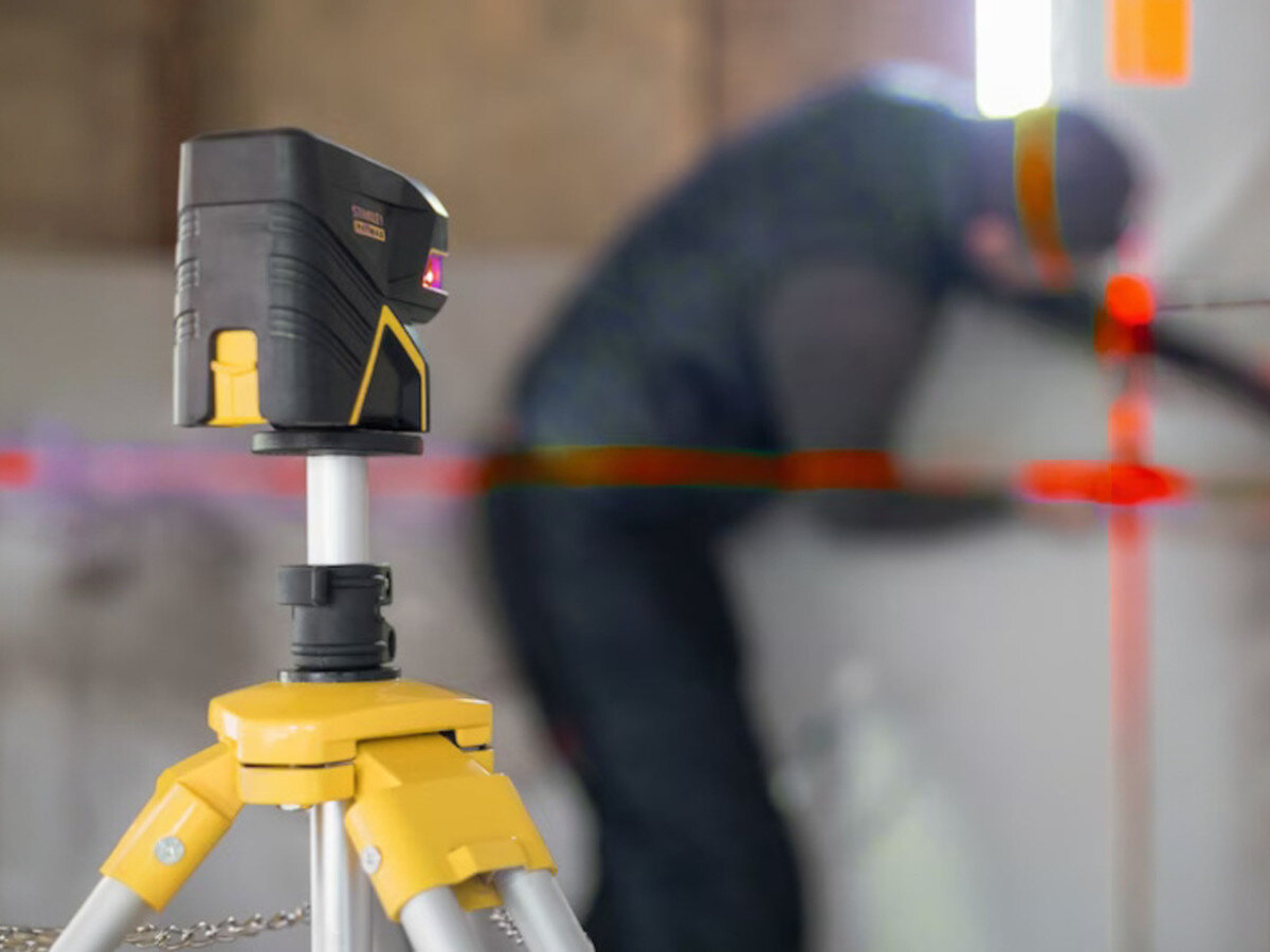 Laser punktowo-krzyżowy STANLEY FMHT1-77414, laser, budowa, pomiar, praca, Laser na statywie wyznacza czerwone linie na ścianie podczas prac budowlanych.