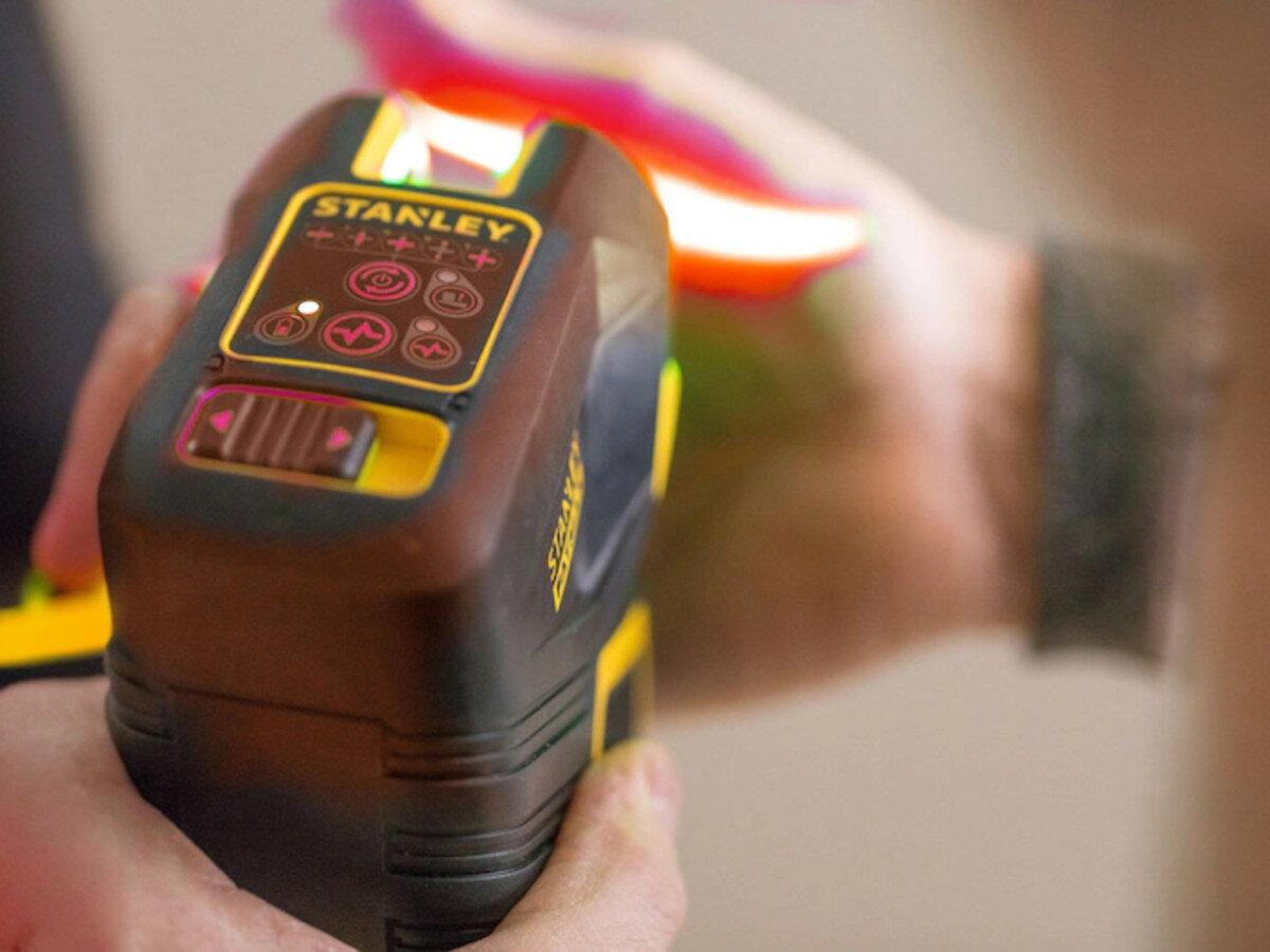 Laser punktowo-krzyżowy STANLEY FMHT1-77414, odporność, guma, upadek, ochrona, Zbliżenie na panel kontrolny lasera z podświetlanymi ikonami i przyciskami.