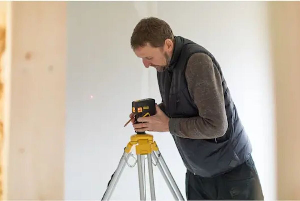 Laser punktowy STANLEY FMHT1-77413, 40, wiązki, punkty, energia, mężczyzna obsługuje laser na statywie