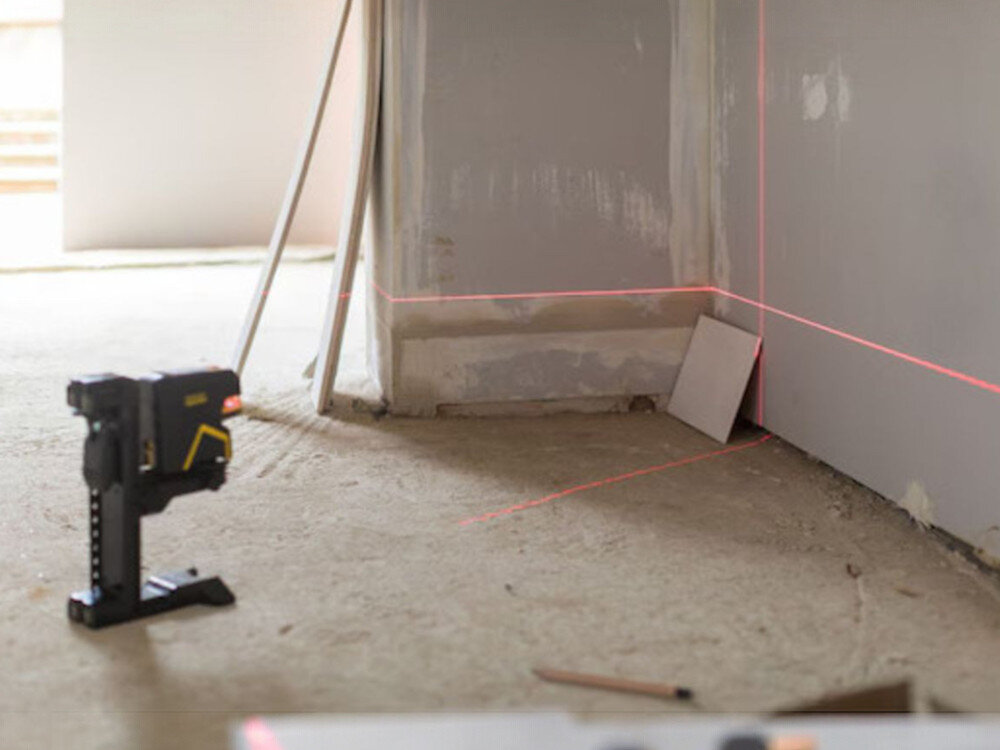 Laser punktowo-krzyżowy STANLEY FMHT1-77415, punkty, pion, poziom, kąt, Laser na uchwycie wyznaczający poziom i pion na ścianie w surowym wnętrzu.