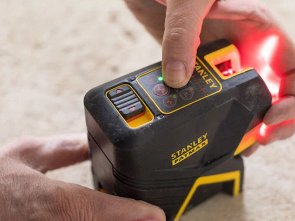 Laser punktowo-krzyżowy STANLEY FMHT1-77415, magnes, statyw, gwint, uchwyt, Obsługa panelu kontrolnego lasera Stanley Fatmax; widoczna czerwona wiązka światła.