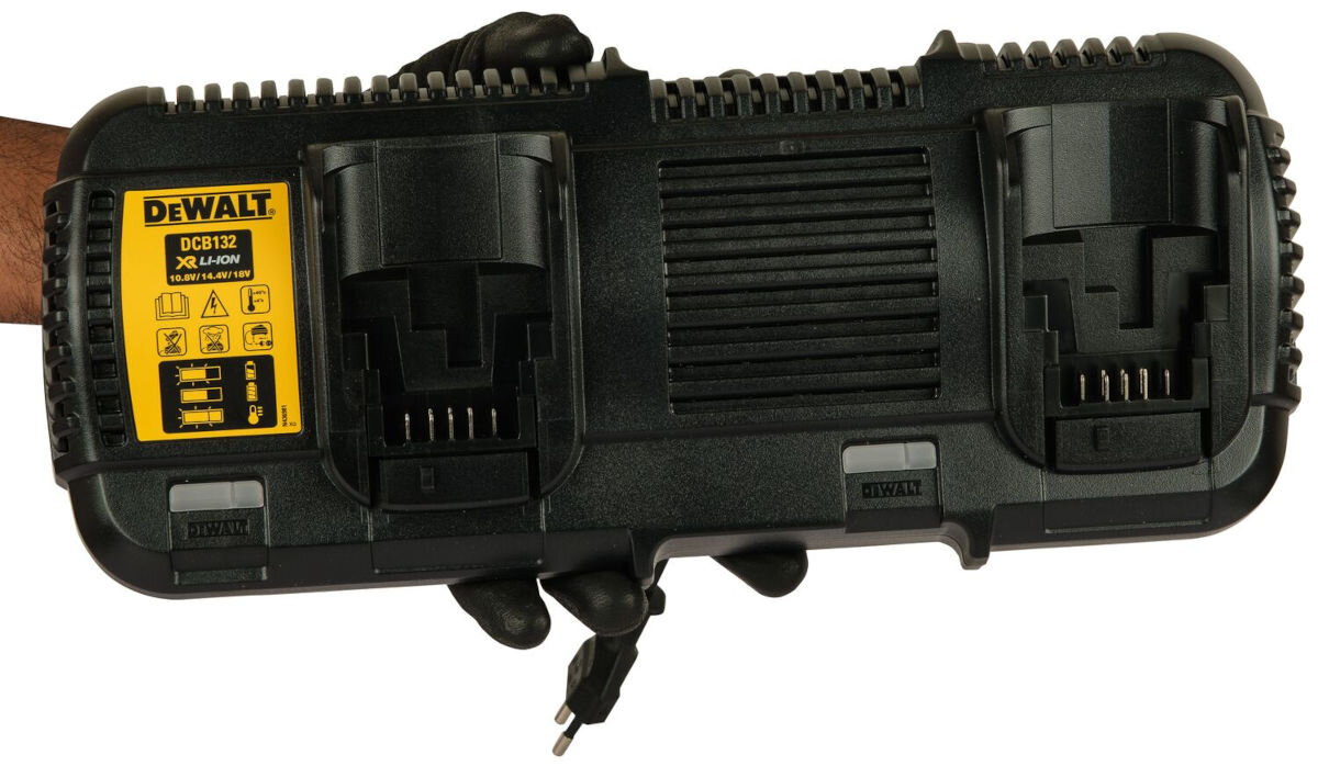 Ładowarka DEWALT DCB132 10.8/18V 4A, moc, ładowanie, remont, budowa, na białym tle dłoń trzyma ładowarkę od frontu na wprost