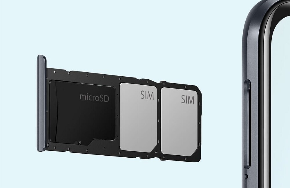 Obraz przedstawia tackę na karty z miejscami na microSD i dwie karty SIM, obok fragment obudowy smartfona.