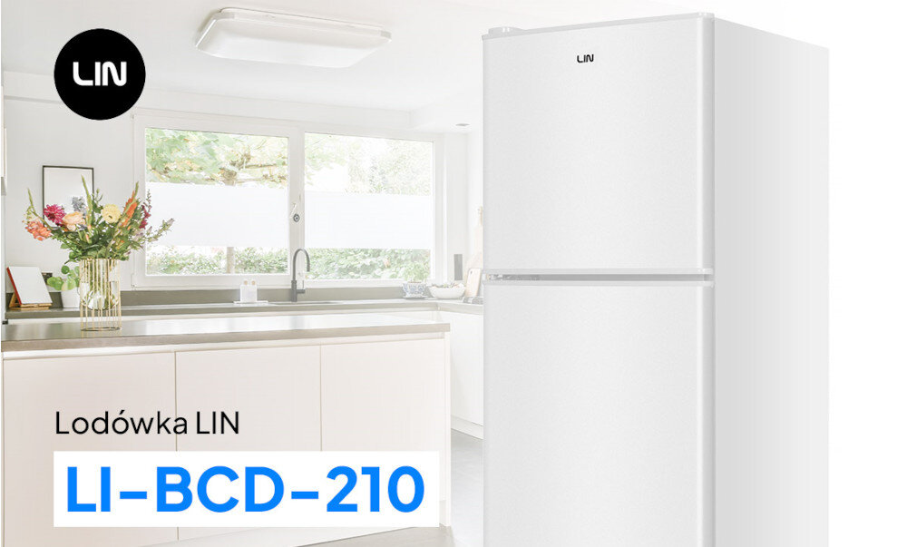 Biała lodówka z logo LIN, model LI-BCD-210, stoi w jasnej kuchni z dużymi oknami i blatem z kwiatami w wazonie.