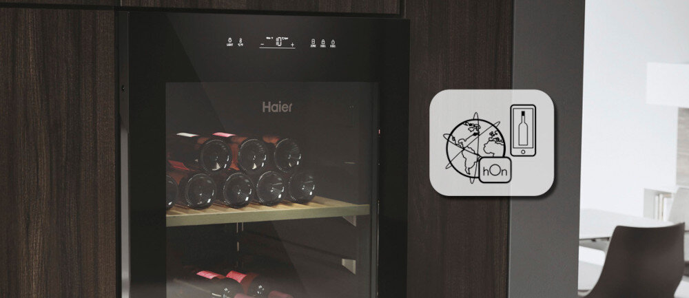 Chłodziarka do wina z widocznymi butelkami na drewnianych półkach, z logo Haier na drzwiach. Obok znajduje się ikona z grafiką globu, butelki i napisem \'hOn\'.