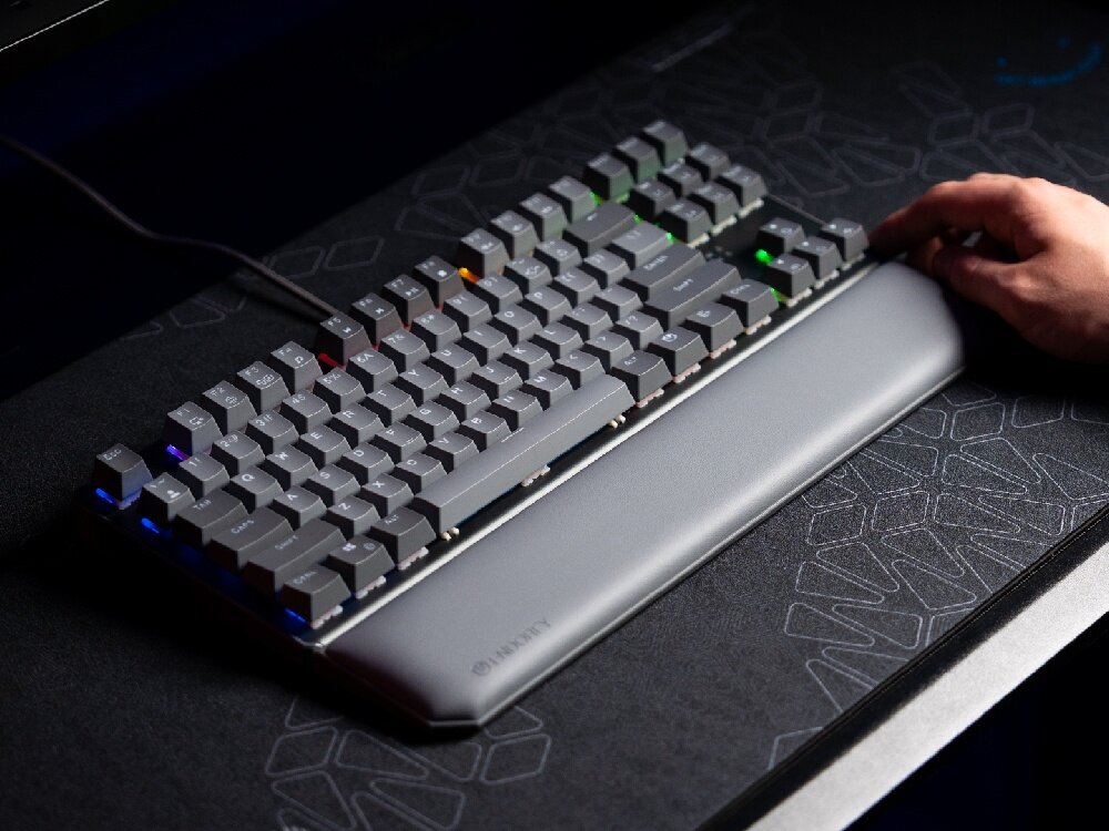Na obrazie widoczna jest klawiatura mechaniczna z podświetleniem RGB, z ręką naciskającą jeden z klawiszy. Na podpórce pod nadgarstki znajduje się logo \'ENDORFY\'.