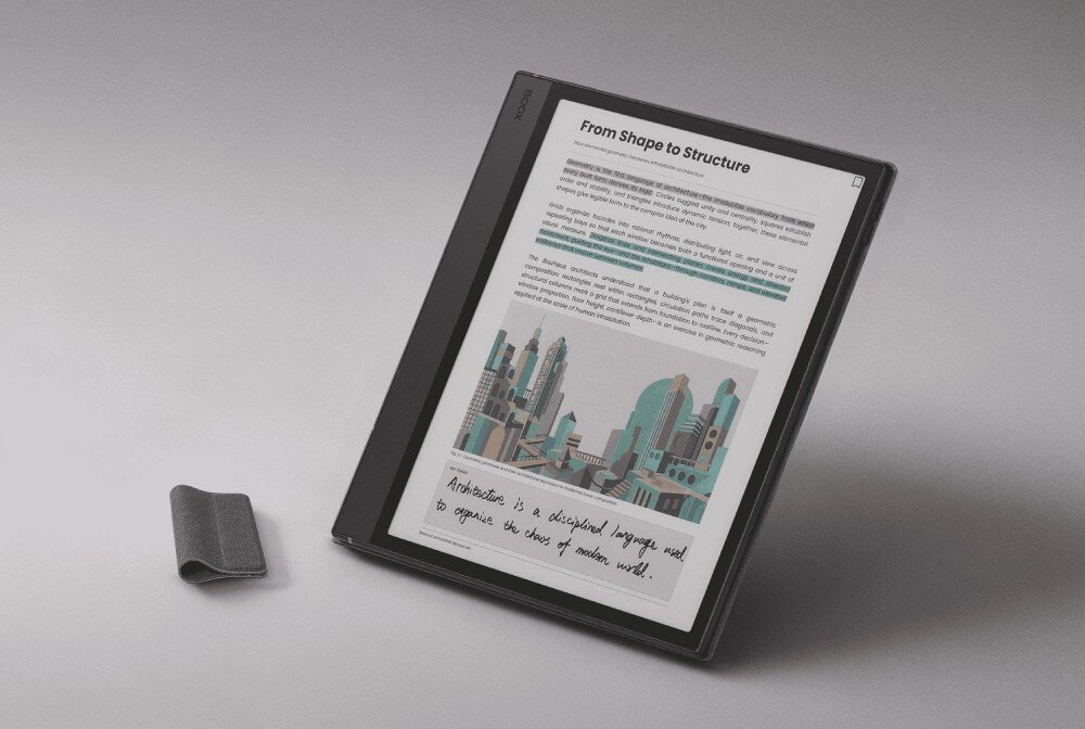 Etui na Onyx Boox Note Air 5 C/6 C ONYX Czytnik e-booków w etui stojący pod kątem, wyświetlający tekst, grafikę z wieżowcami oraz odręczną notatkę, obok leży małe zapięcie