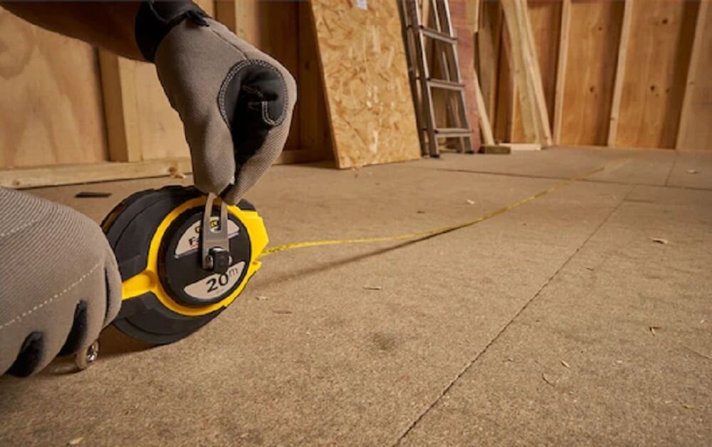Miara zwijana STANLEY 0-34-133 (20 m), taśma, zasięg, precyzja, wytrzymałość, osoba odmierza miarą dystans do ściany w remontowanym budynku