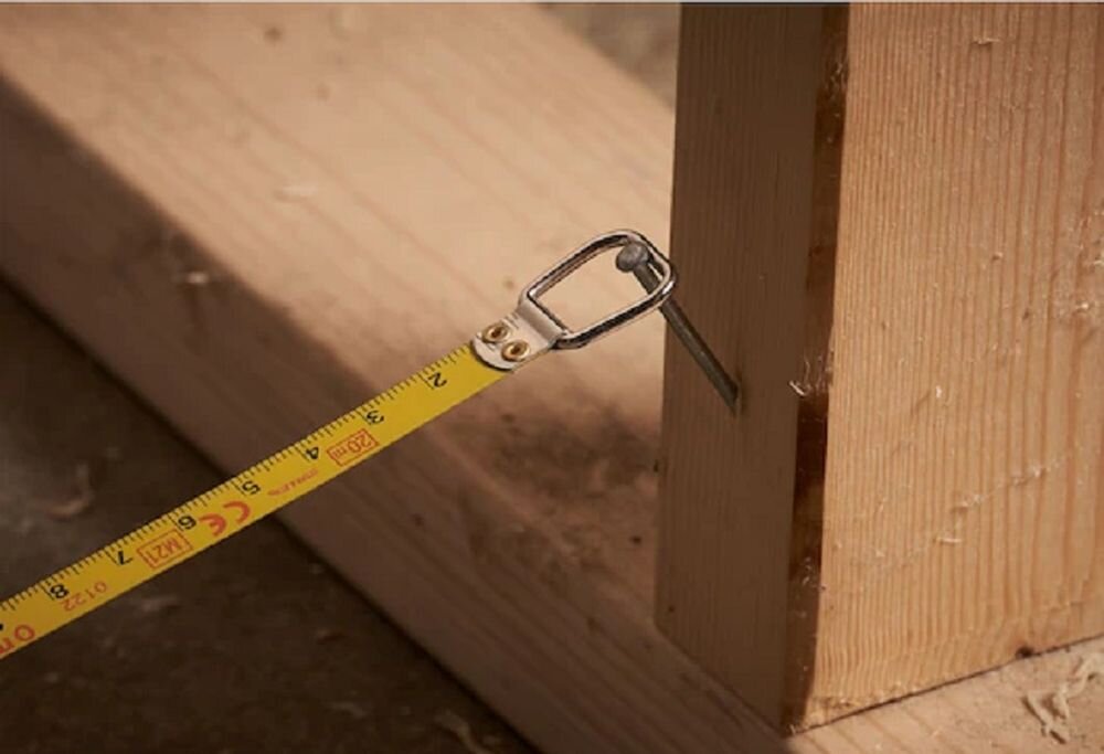 Miara zwijana STANLEY 0-34-133 (20 m), wszechstronność, blokada, cyfry, profesjonaliści, zbliżenie na haczyk końcowy miarki przyczepiony do gwoździa w desce