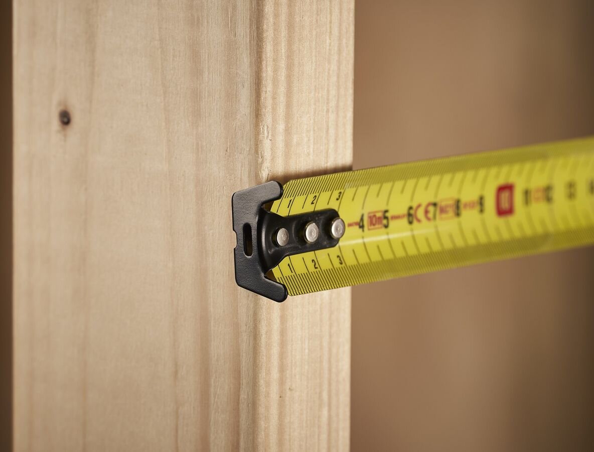Miara zwijana STANLEY 0-33-811 (10 m), blokada, zwijanie, cyfry, komfort, zbliżenie na początek miarki zahaczonej o kawałek deski podczas budowy