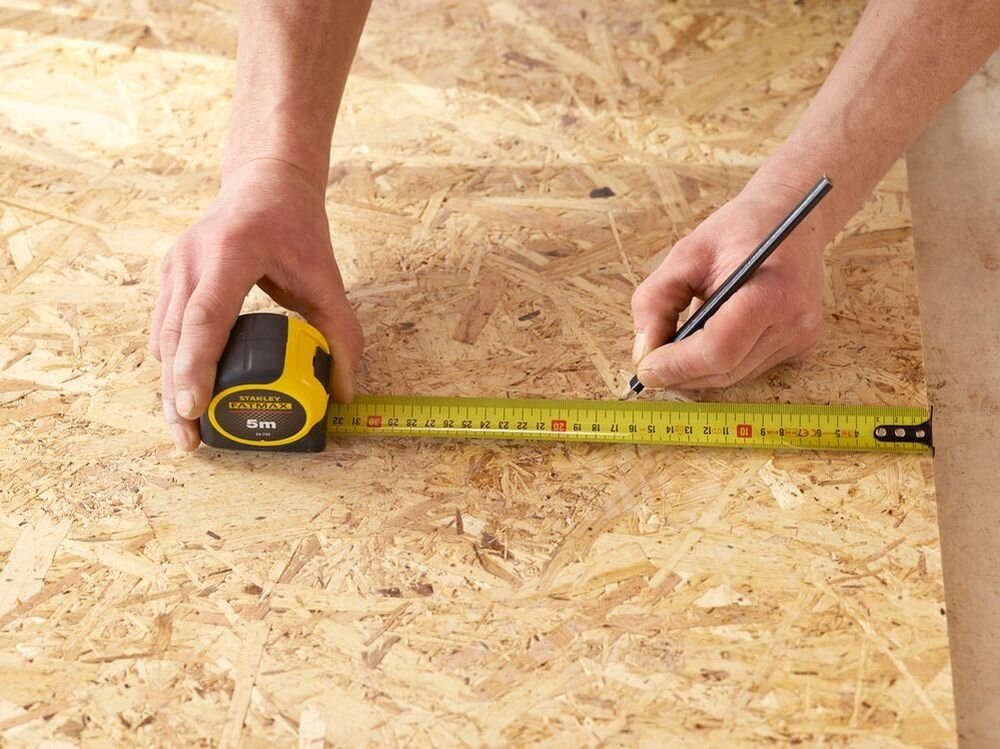 Miara zwijana STANLEY 33-720 (5 m), solidna, miara, dystans, precyzja, osoba odmierza na desce miarą dystans