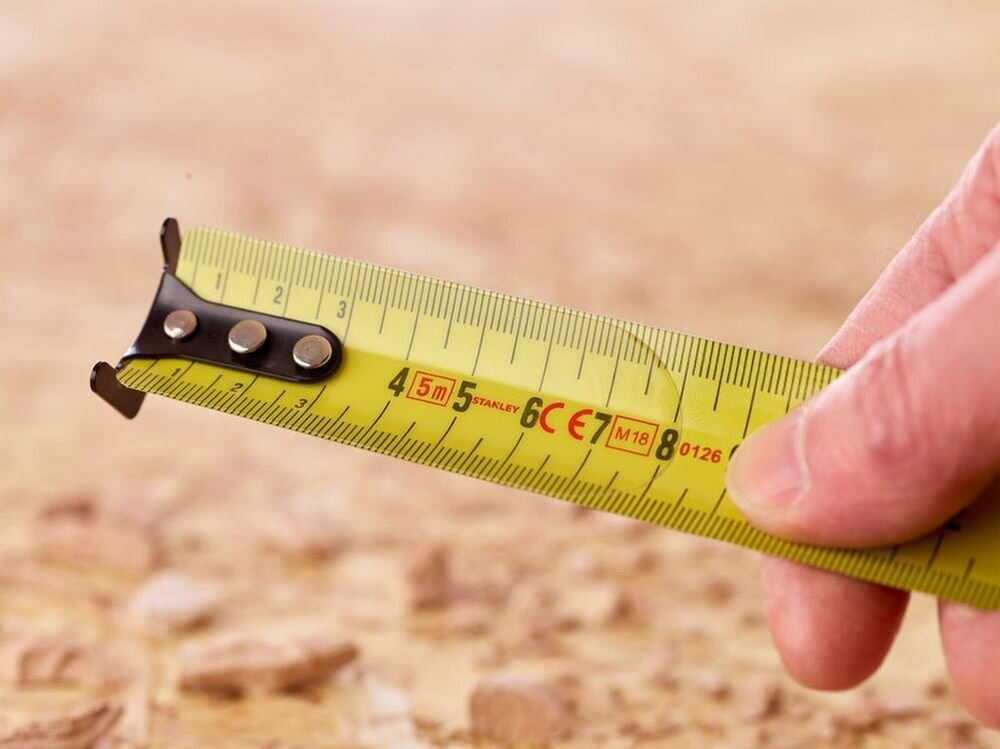 Miara zwijana STANLEY 33-720 (5 m), BladeArmor, ochrona, hak, wytrzymałość, zbliżenie na zaczep i hak miary zwijanem w tle drewno