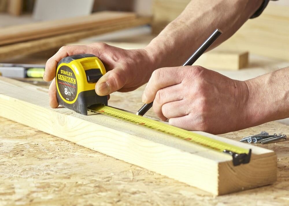 Miara zwijana STANLEY 0-33-728 (8 m), solidna, miara, dystans, precyzja, osoba odmierza na desce miarą dystans
