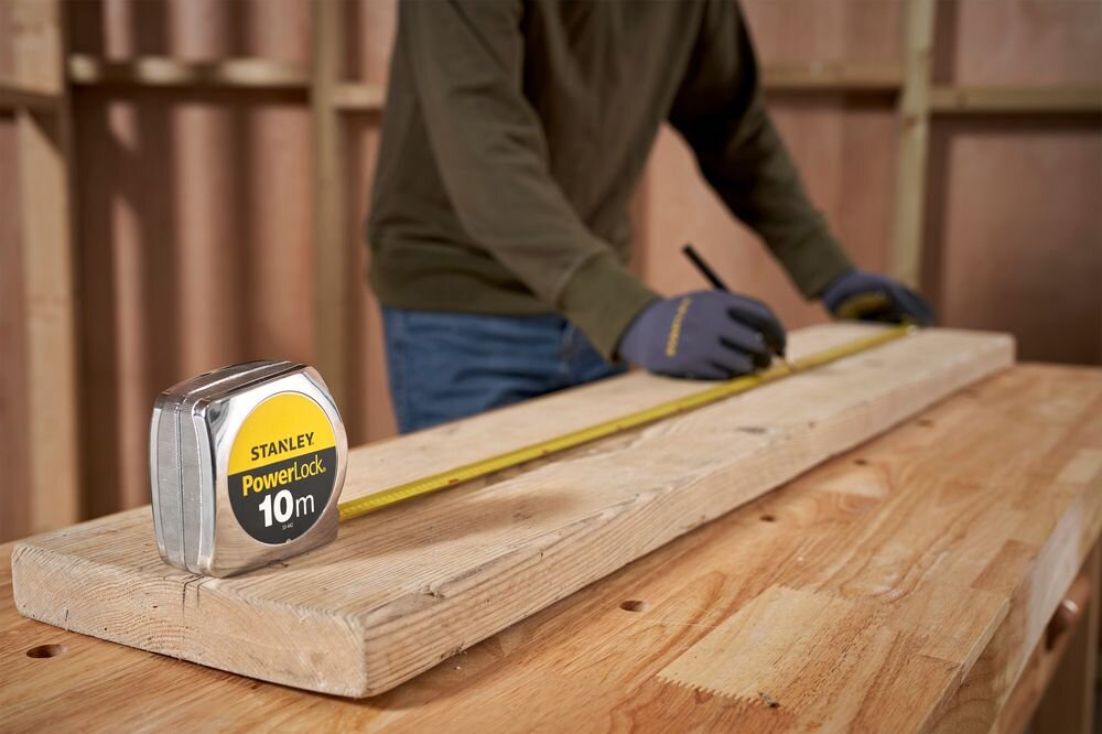Miara zwijana STANLEY 1-33-442 (10 m), precyzja, taśma, zwijanie, wytrzymałość, osoba rozwija miarę przy ścianie remontowanej