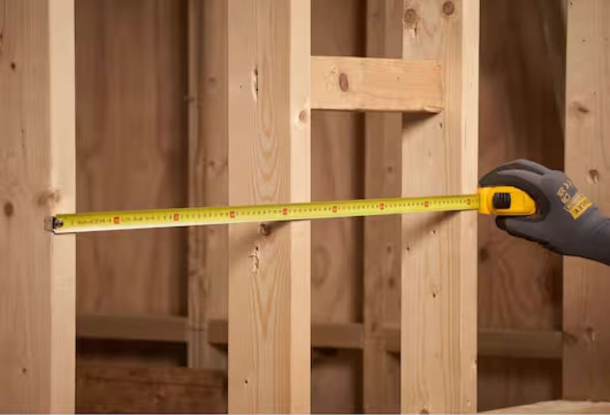 Miara zwijana STANLEY 0-30-497 (5 m), taśma, dokładność, odczyt, zaczep, Żółta miarka zwijana STANLEY 5 m wysunięta na blacie obok śrubokręta i kołków montażowych.