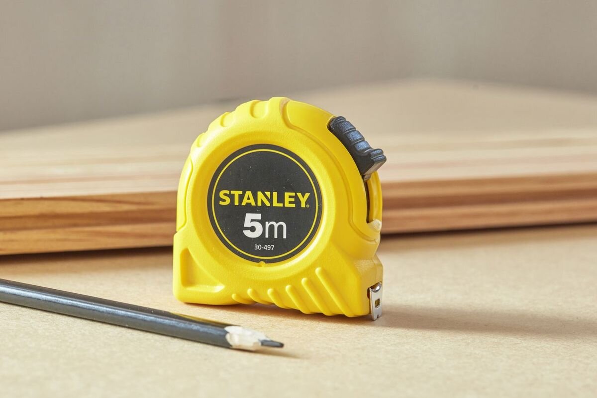 Miara zwijana STANLEY 0-30-497 (5 m), precyzja, pomiar, taśma, zwijanie, Pomiar odległości między drewnianymi słupkami konstrukcyjnymi żółtą miarką zwijaną