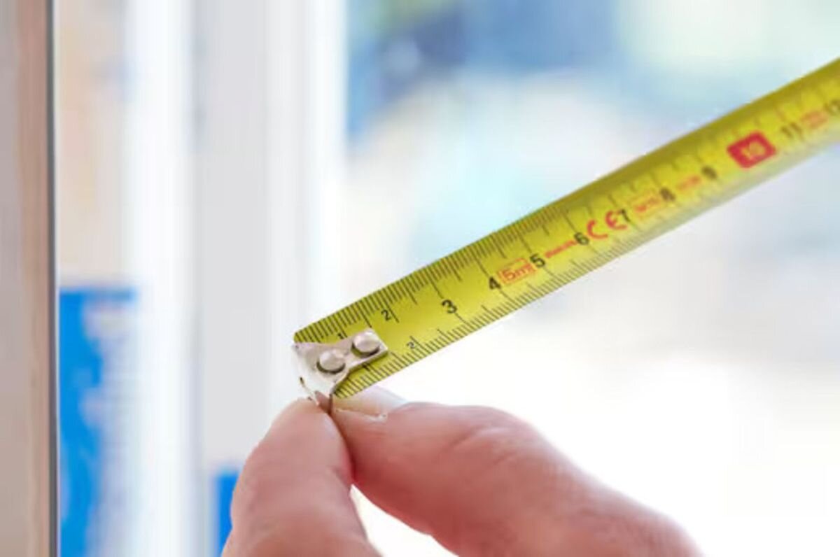 Miara zwijana STANLEY 0-30-497 (5 m), uchwyt, lekkość, mechanizm, wygoda, Zbliżenie na miarkę zwijaną mierzącą szczelinę przy oknie