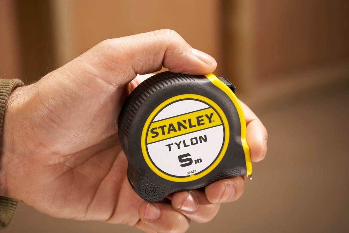 Miara zwijana STANLEY S/30-697-0, obudowa, blokada, chwyt, pasek, dłoń trzyma pewnie miarkę do zwijania