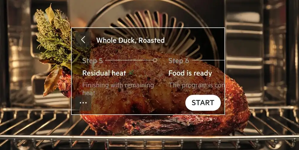 W piekarniku znajduje się pieczona kaczka z ziołami. Na obrazie widoczny jest tekst: \'Whole Duck, Roasted\', \'Step 5\', \'Residual heat\', \'Finishing with remaining heat\', \'Step 6\', \'Food is ready\', \'The program is con\', \'START\'.