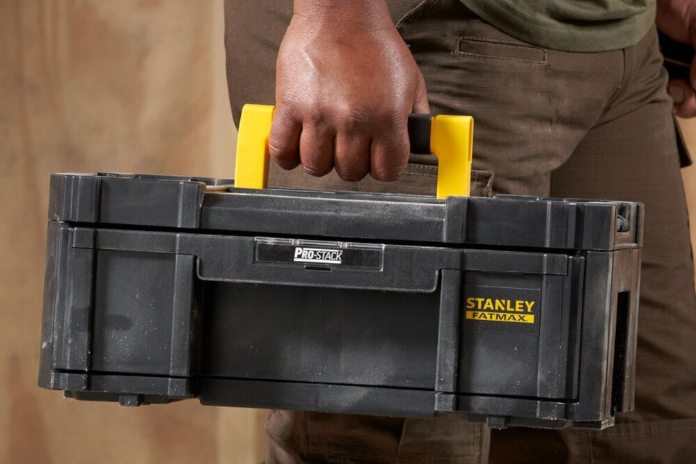 Moduł STANLEY Fatmax Pro Stack III FMST1 71968 pomieszczenie osoba trzyma moduł w dłoni duża rękojeść z wysokiej jakości tworzywa sztucznego stabilny chwyt komfort przenoszenia ergonomiczny kształt waga około 3,5 kg