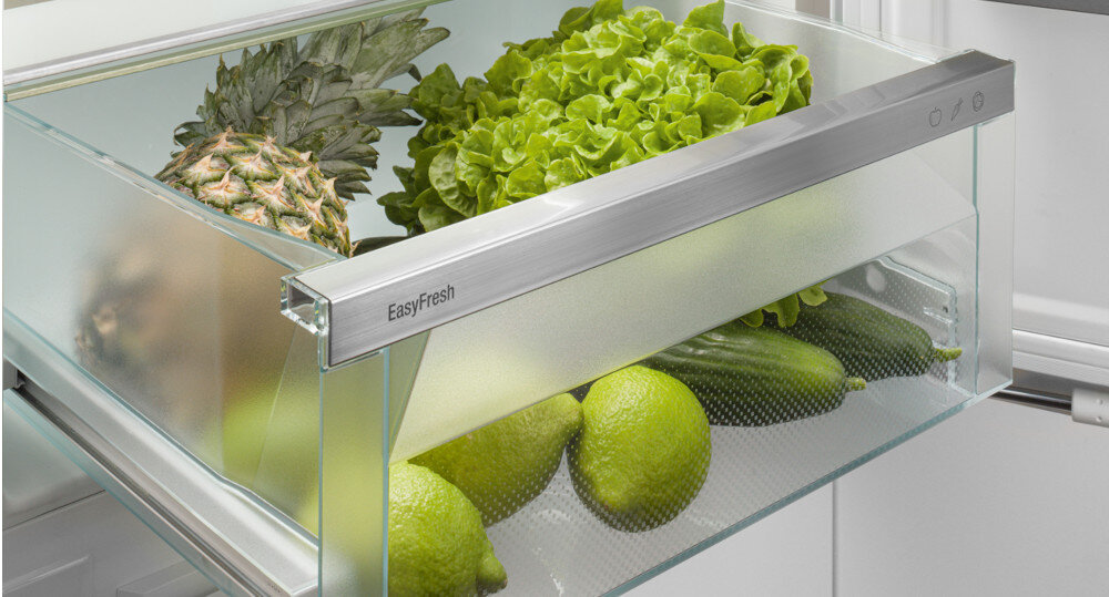 Szklana szuflada lodówki z napisem \'EasyFresh\' zawiera ananasa, sałatę, ogórki i limonki.