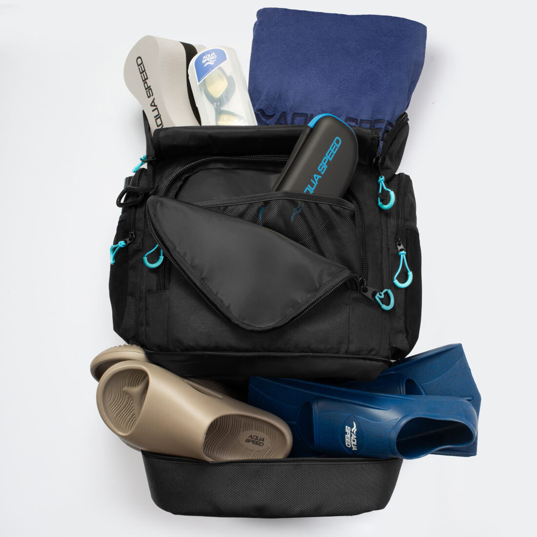 Czarny plecak z niebieskimi suwakami, wypełniony akcesoriami pływackimi, takimi jak klapki, ręcznik i okulary. Widoczne logo \'AQUA SPEED\' na kilku przedmiotach.