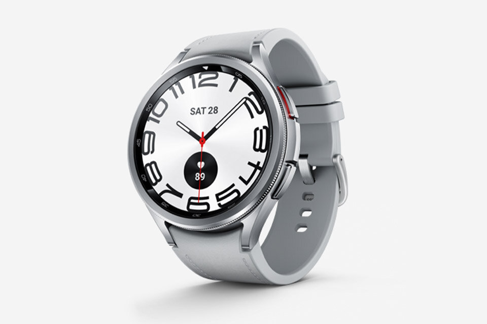 Srebrny smartwatch z okrągłą tarczą, na której widoczny jest czas, data \'SAT 28\' oraz liczba \'89\'. Pasek zegarka jest szary, a na tarczy znajdują się duże cyfry godzinowe.
