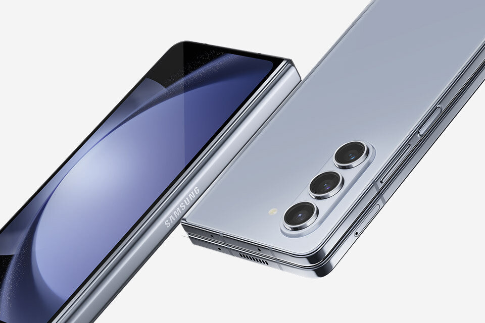 Na obrazie widoczny jest smartfon z trzema aparatami z tyłu i logo \'SAMSUNG\' na boku. Urządzenie ma metaliczną obudowę i jest częściowo otwarte, ukazując ekran.