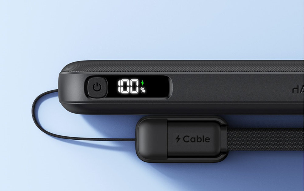 Czarny powerbank z wyświetlaczem pokazującym \'100%\' oraz przyciskiem zasilania. Obok znajduje się kabel z napisem \'Cable\'.