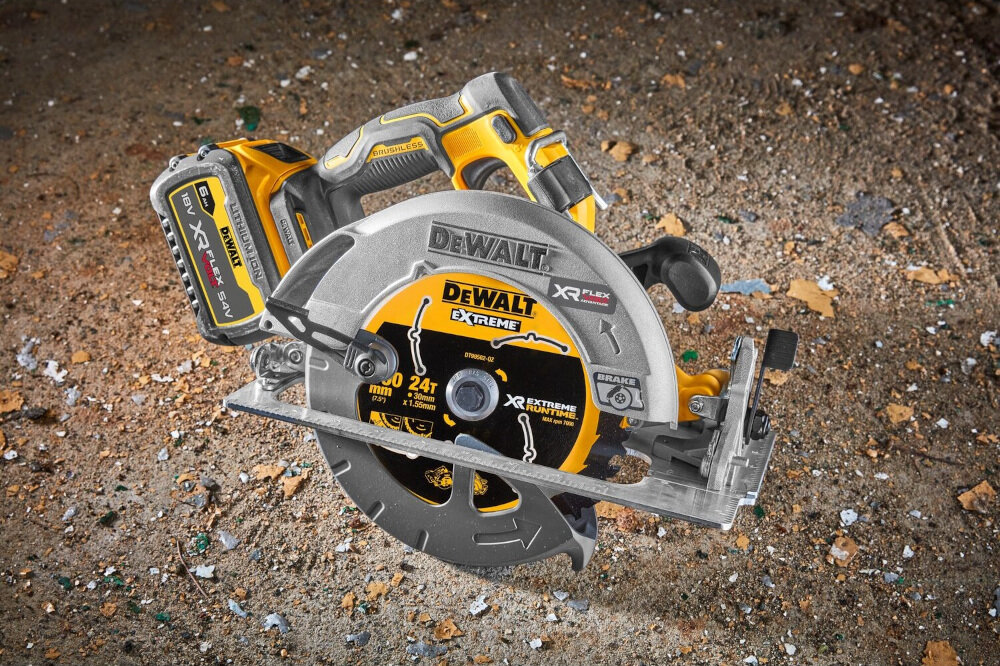Na obrazie widoczna jest pilarka tarczowa z logo DEWALT, umieszczona na ziemi pokrytej drobnymi odpadkami. Na pile widnieje napis \'XR FLEXVOLT\' oraz \'24T\'.
