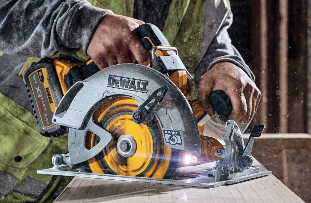 Osoba trzyma pilarkę tarczową z widocznym logo DEWALT, która przecina drewnianą powierzchnię. Na urządzeniu widoczny jest napis \'XR 18V\' oraz \'BRUSHLESS\'.