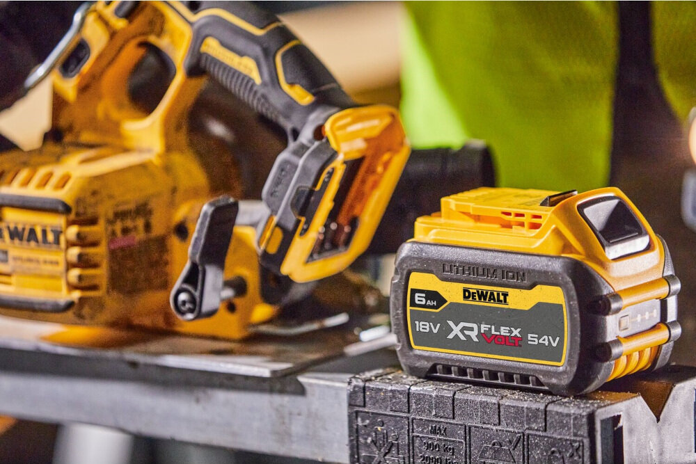 Na obrazie widoczna jest pilarka tarczowa oraz akumulator marki DEWALT. Akumulator ma oznaczenia: \'LITHIUM ION\', \'DEWALT\', \'6 AH\', \'18V XR FLEXVOLT 54V\'.