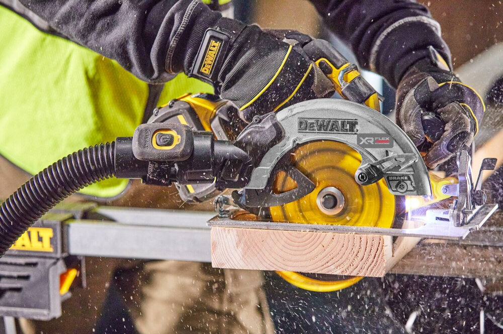 Osoba używa pilarki tarczowej z widocznym logo \'DEWALT\' do cięcia drewnianej belki. W tle widać elementy warsztatu i unoszące się wióry drzewne.