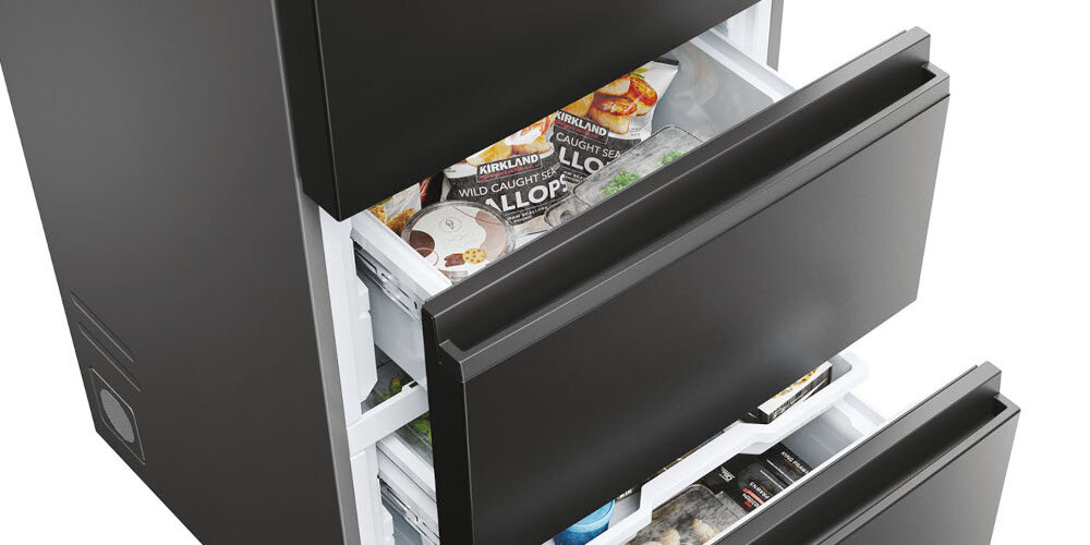 Czarna lodówka z otwartymi szufladami, wypełnionymi różnymi produktami spożywczymi. Widoczny tekst na opakowaniach: \'KIRKLAND WILD CAUGHT SEA SCALLOPS\'.