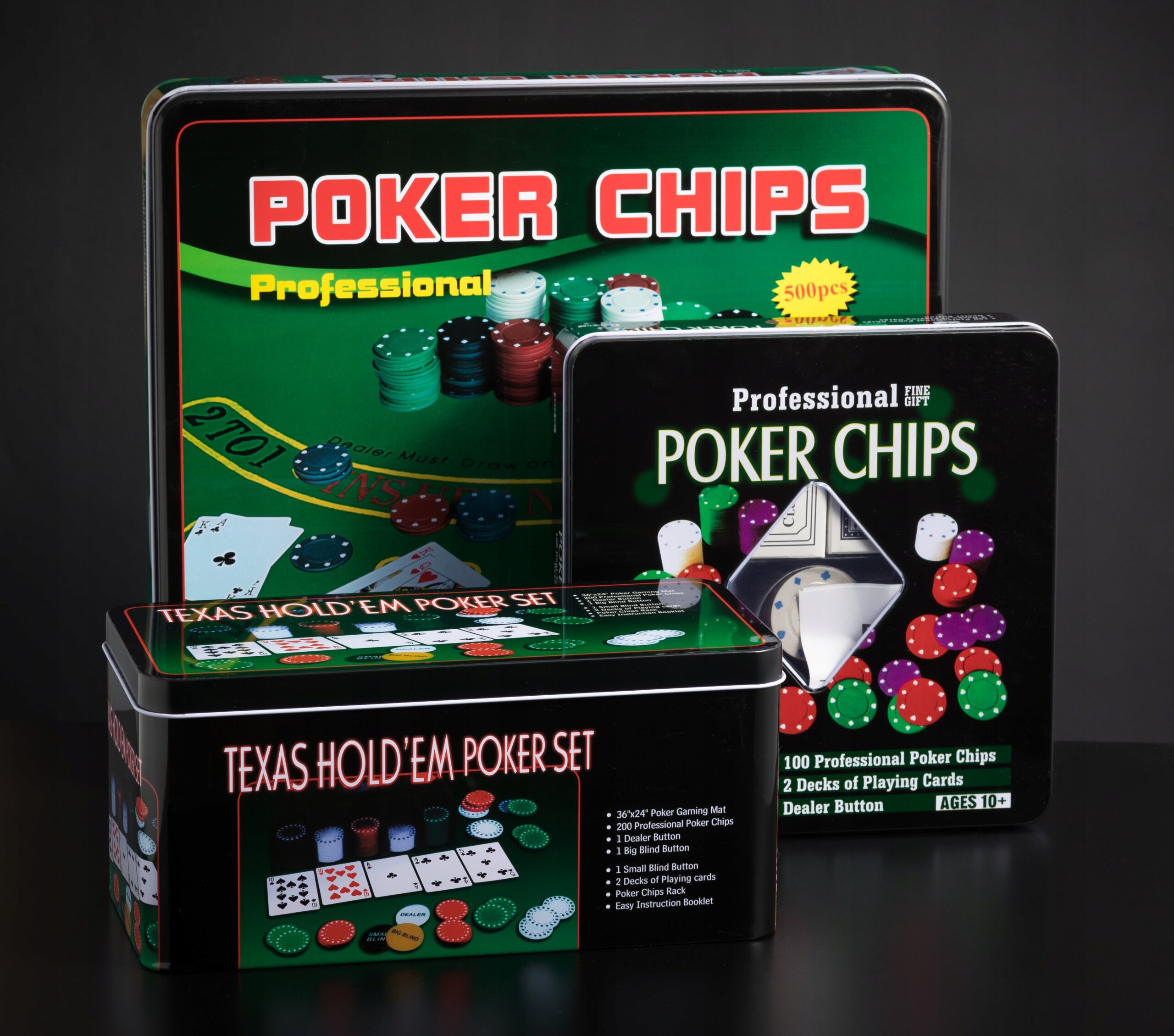Na obrazie widoczne są trzy metalowe pudełka z zestawami do pokera, każde z napisem \'POKER CHIPS\' lub \'TEXAS HOLD\'EM POKER SET\'. Pudełka mają kolorowe ilustracje żetonów i kart do gry.