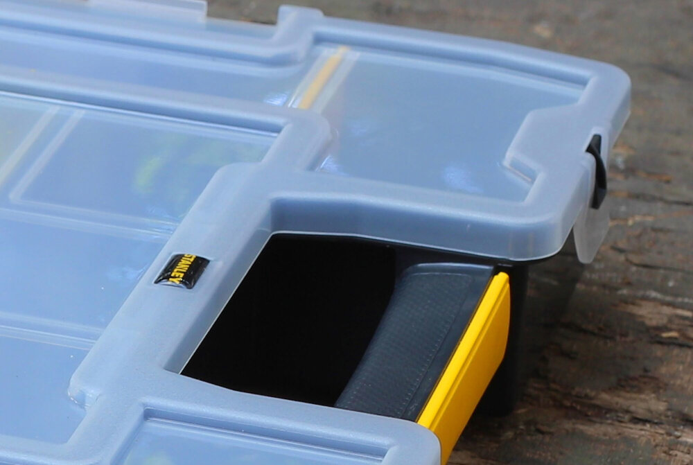 Organizer STANLEY Sort Master Junior 1-97-483 zbliżenie na pokrywę i uchwyt drewniane podłoże z wytrzymałego tworzywa długa żywotność wymiary 290 × 375 × 67 mm pojemność 5,43 l