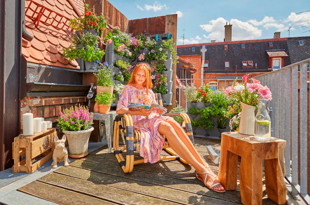 Ogród wertykalny GARDENA NatureUp 13153-20 balkon taras niebo domy osoba siedzi na krześle czyta magazyn w tle ogród wertykalny pionowy ogród mały ogród na balkonie zielona przestrzeń