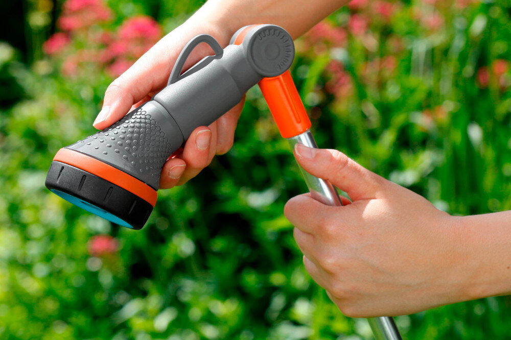 Lanca zraszająca GARDENA 18334-20 Comfort rozmazane zielone tło osoba reguluje położenie głowicy płynna bezstopniowa regulacja ilości wody obsługa jednym palcem kontrola zużycia wody dopasowanie strumienia do aktualnych potrzeb