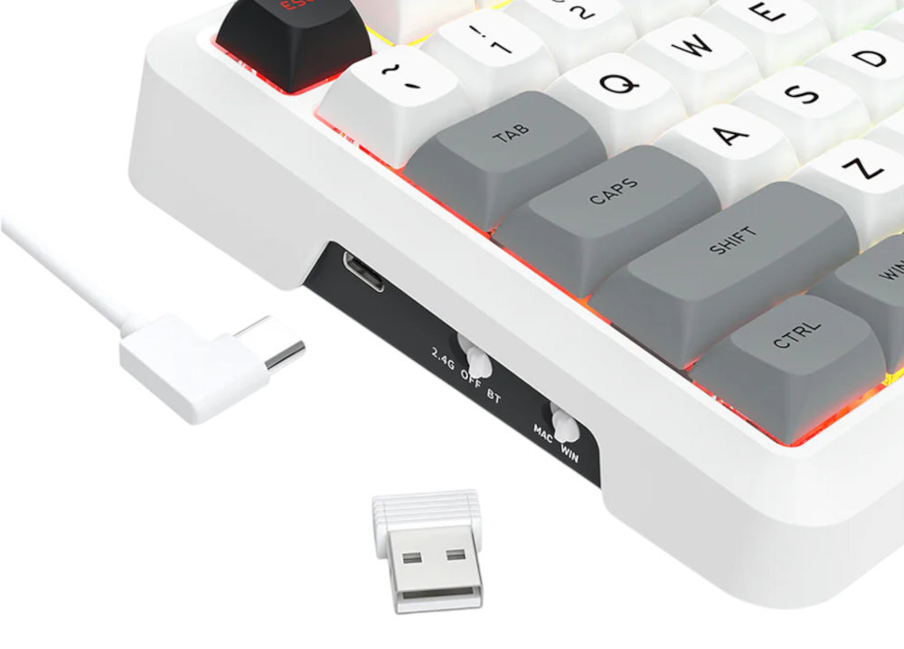 Fragment białej klawiatury z szarymi i białymi klawiszami, z widocznymi napisami: \'TAB\', \'CAPS\', \'SHIFT\', \'CTRL\'. Obok klawiatury znajduje się biały kabel USB-C oraz adapter USB, a na boku klawiatury widoczne są przełączniki z napisami: \'2.4G\', \'OFF\', \'BT\', \'MAC\', \'WIN\'.