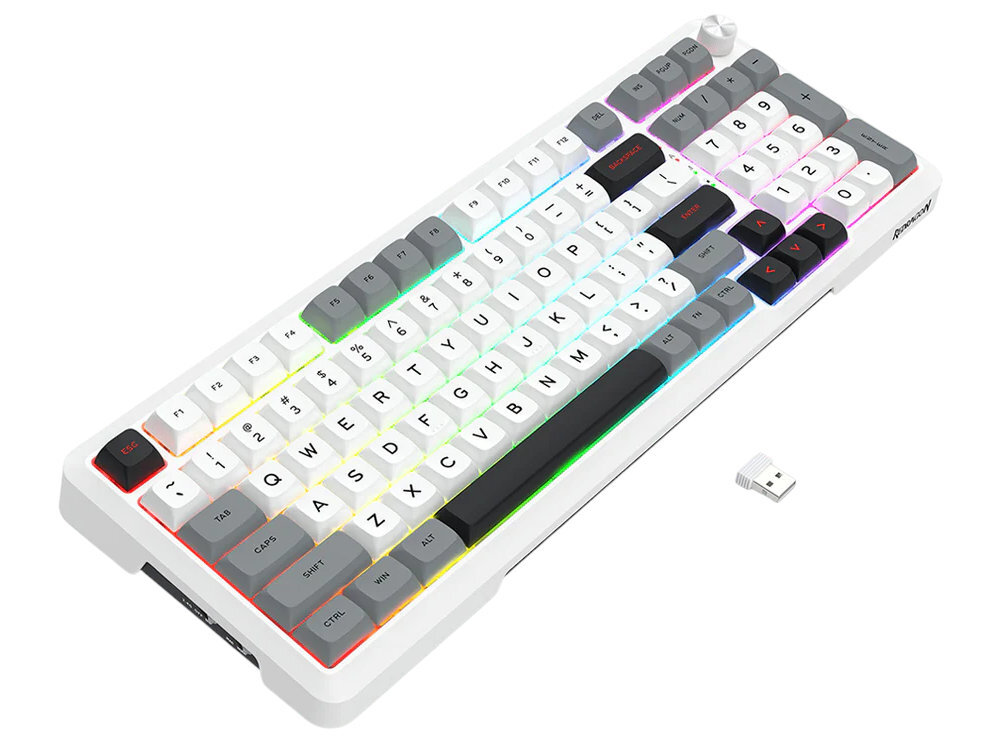 Na obrazie widoczna jest klawiatura z białymi i szarymi klawiszami oraz podświetleniem RGB. Obok klawiatury znajduje się mały adapter USB.