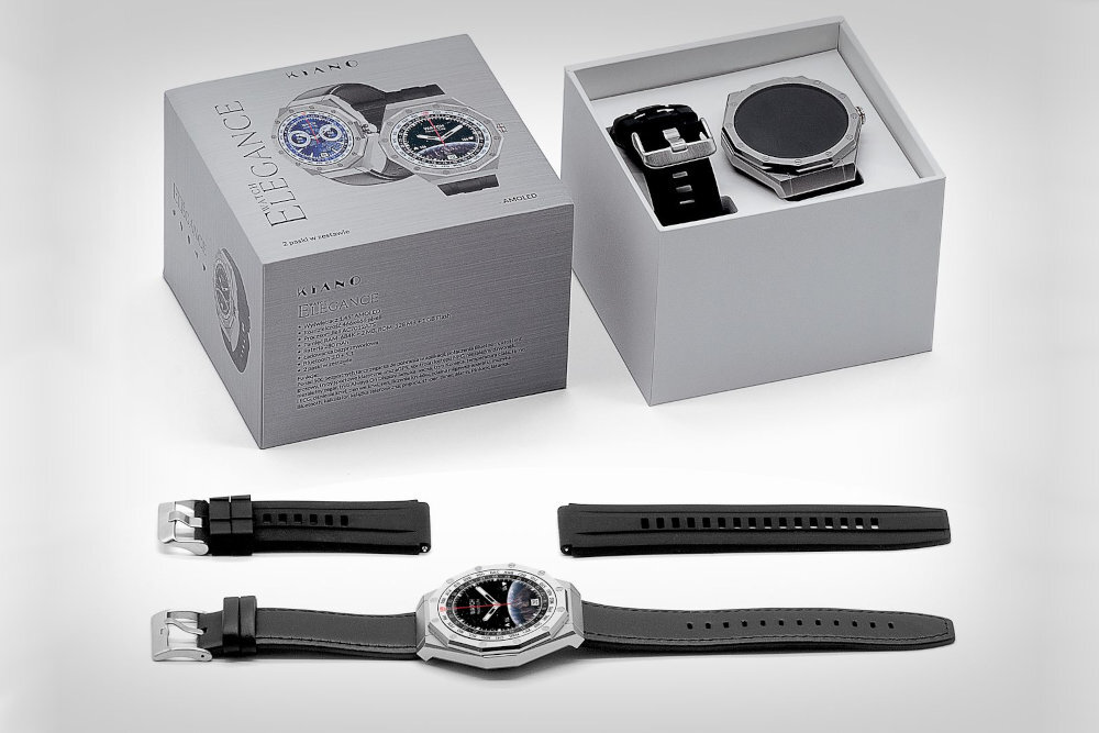 Na obrazie widoczny jest smartwatch KIANO Watch Elegance Srebrny z czarnym paskiem, zaprezentowany obok swojego opakowania. W pudełku znajduje się dodatkowy pasek oraz instrukcja, a na opakowaniu widnieje napis \'KIANO ELEGANCE\'.