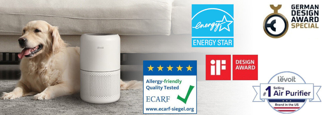 Na obrazie znajduje się biały oczyszczacz powietrza LEVOIT obok psa na dywanie. Widoczne są również logotypy: Energy Star, German Design Award Special, iF Design Award, ECARF oraz informacja \'No. 1 Selling Air Purifier Brand in the US\'.